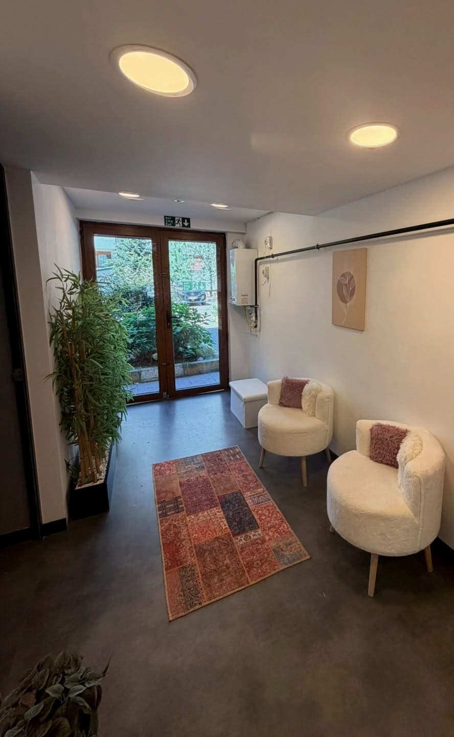 Bekleme alanı, bouclé koltuklar, kilim ve bitkiler